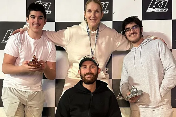 Celine Dion standing on a podium surrounded by her three sons.