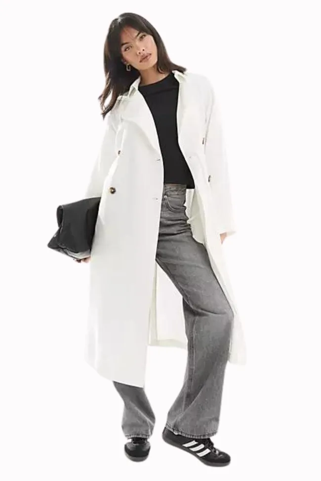 A model wearing a white trench coat from ASOS.
