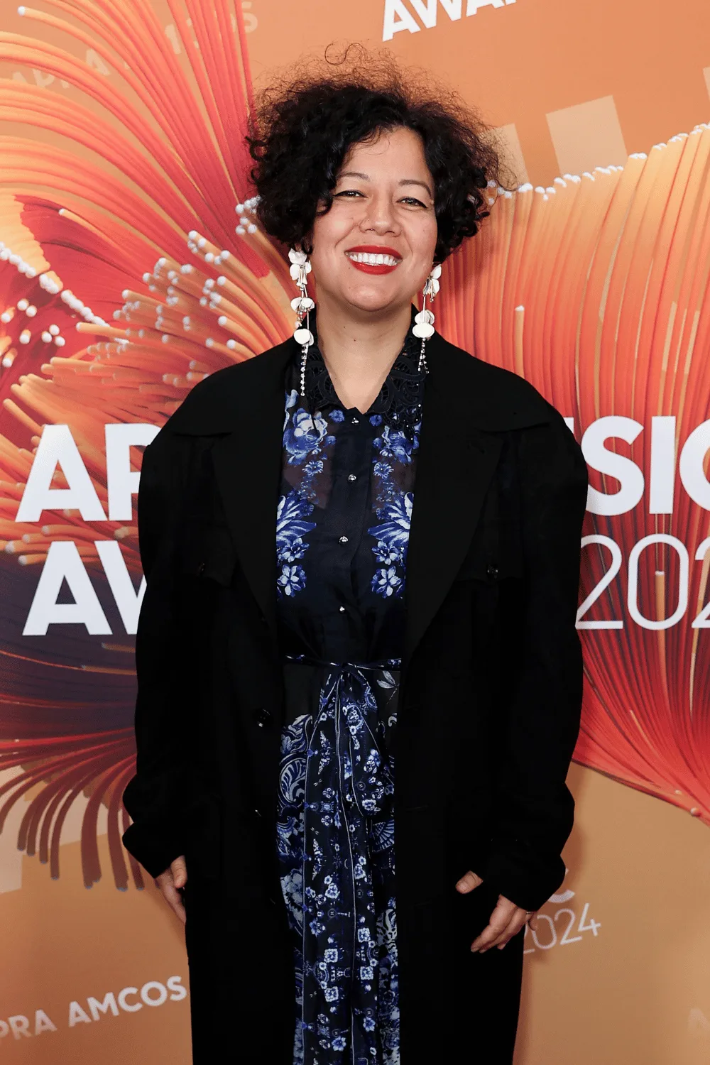 Mahalia Barnes standing in front of an orange backdrop. 