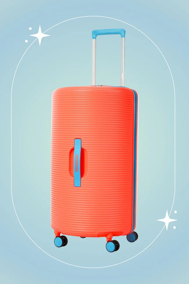Bright orange American Tourister suitcase with blue handle and wheels against a light blue background.