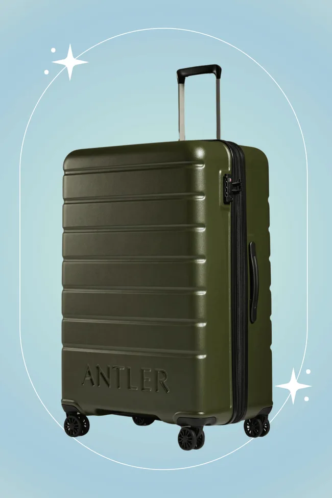 A green Antler hardshell suitcase with retractable handle and wheels against a light blue background with star accents.