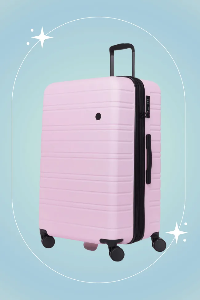 Pink hard-shell suitcase with four wheels and a retractable handle on a blue background.