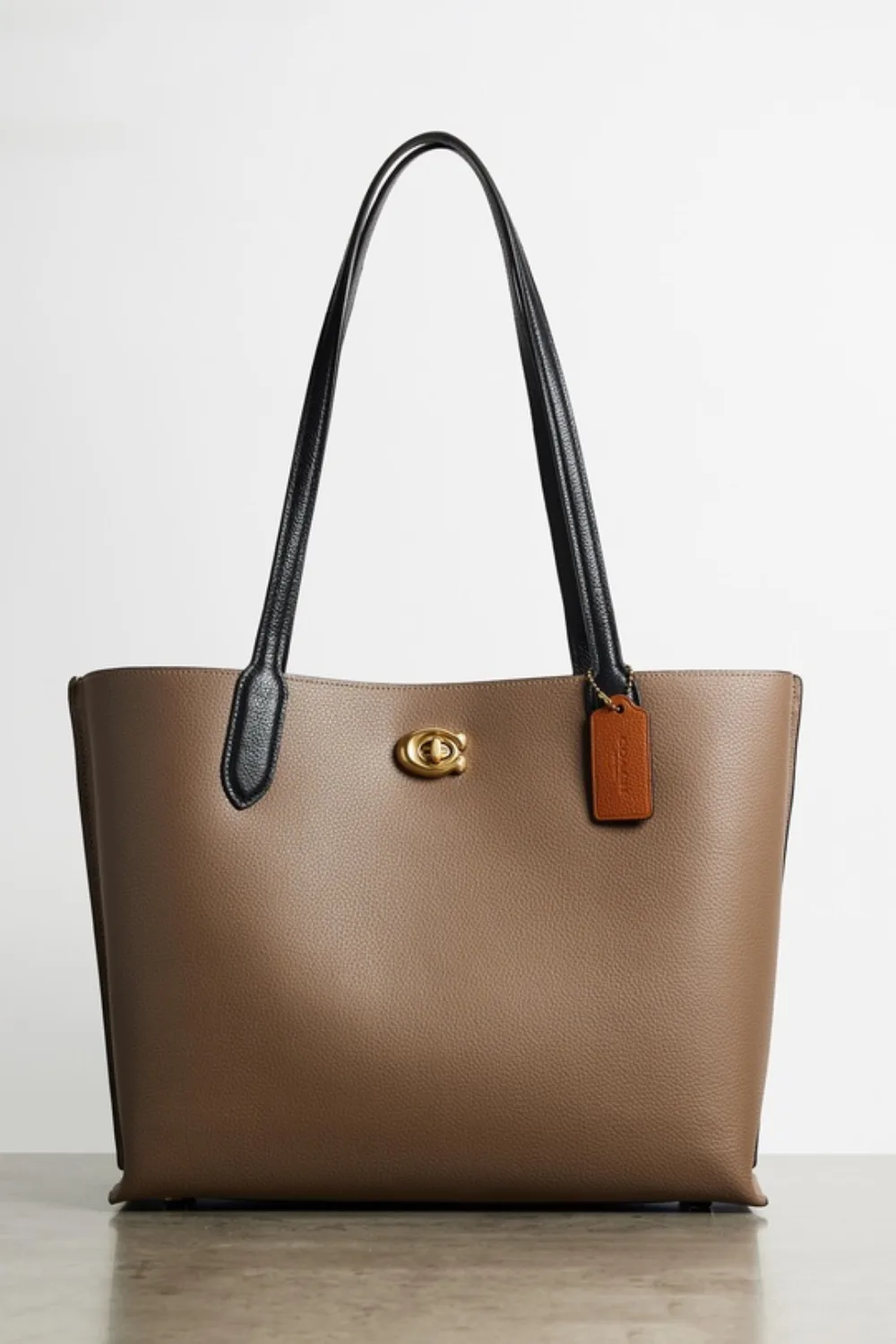 Coach Colourblock brown leather tote bag on stone floor with grey background.