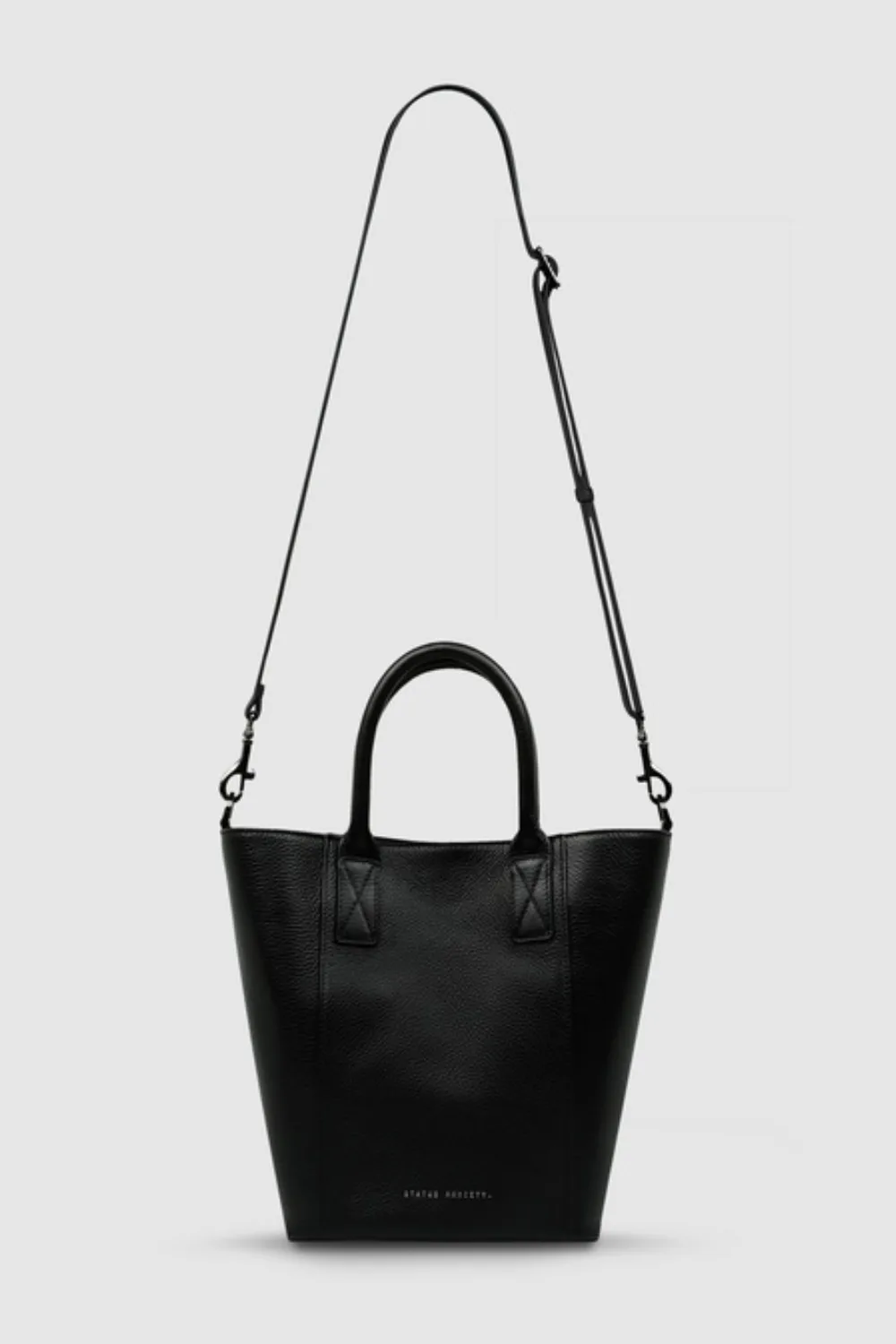 A black Status Anxiety tote bag on a grey background.