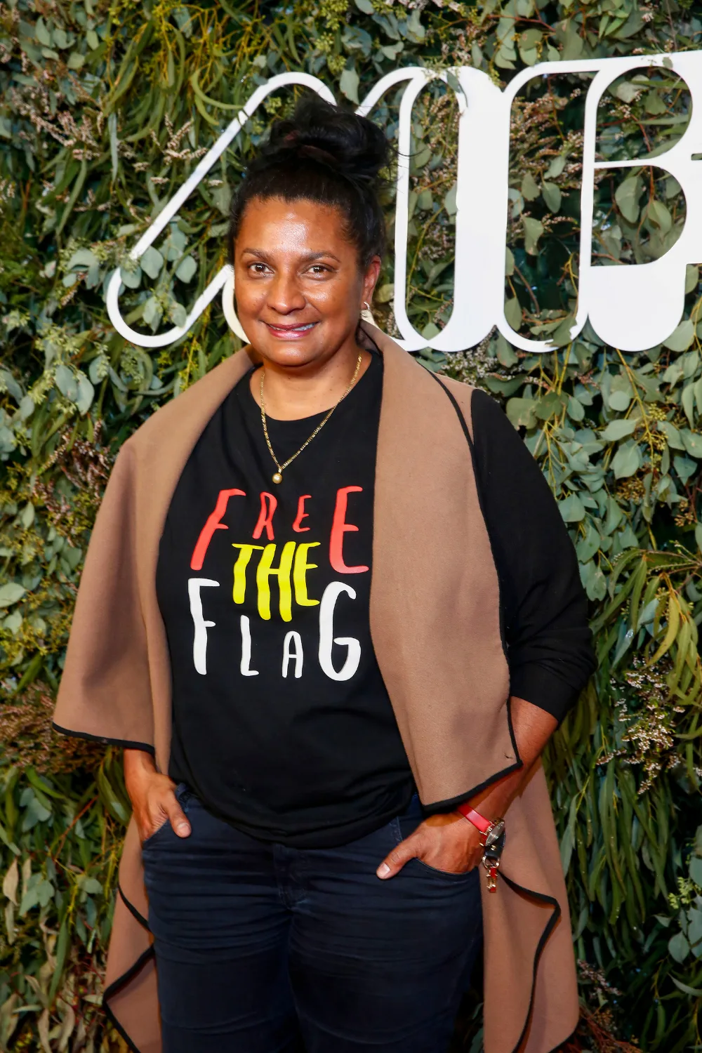 Nova Peris standing in front of green backdrop.