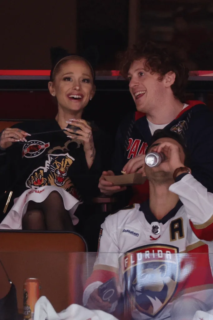 Ariana Grande and Ethan Slater in the grandstand of a football game.