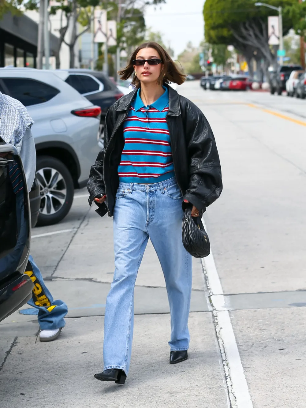 Hailey Bieber wearing polo stripe top with jeans and black jacket