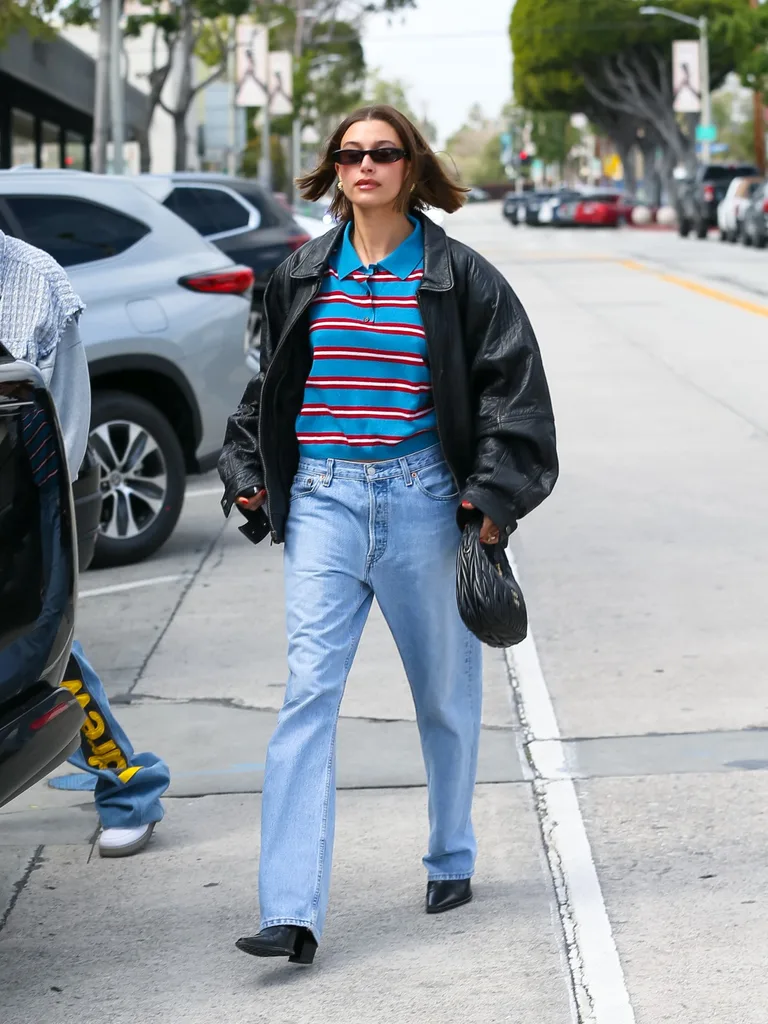 Hailey Bieber wearing polo stripe top with jeans and black jacket