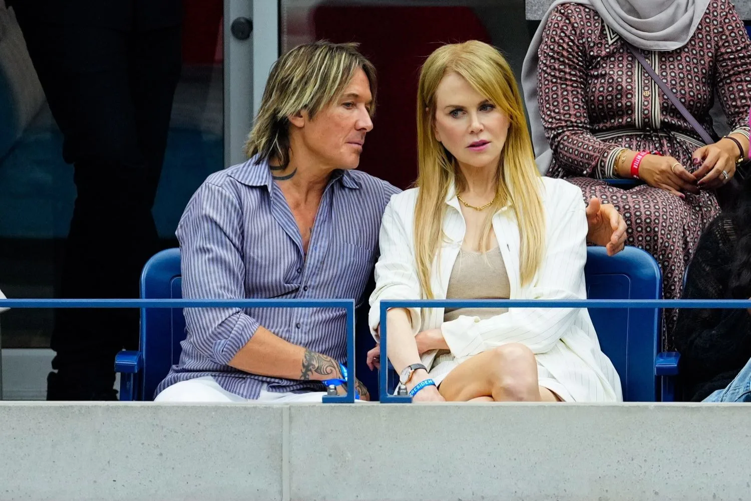 Keith says something interesting to Nicole at a sports match.