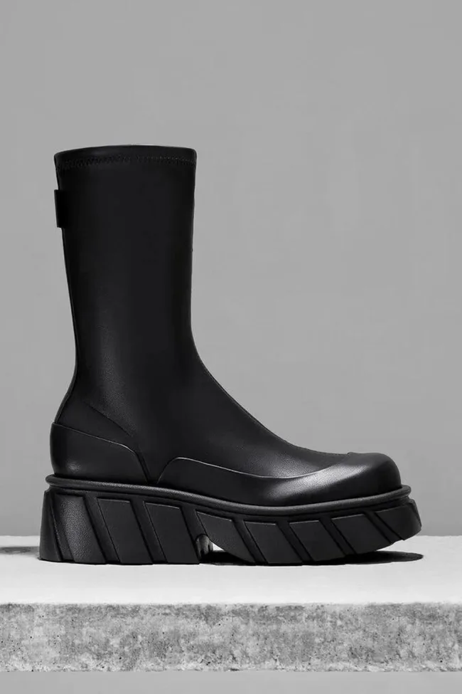 Black chunky platform boot on a gray background.