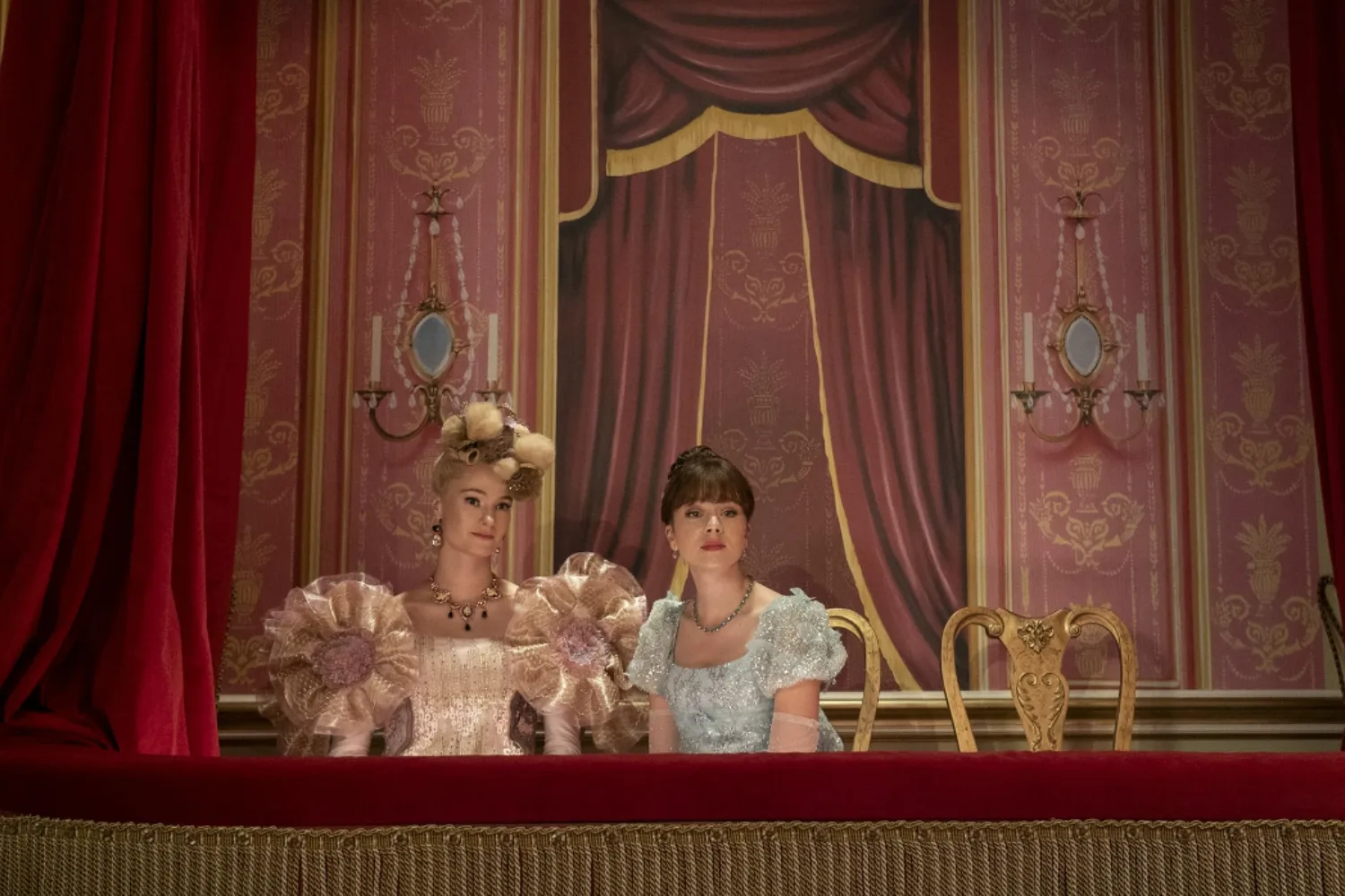 Eloise and Cressida from Bridgerton sitting in a theatre balcony.