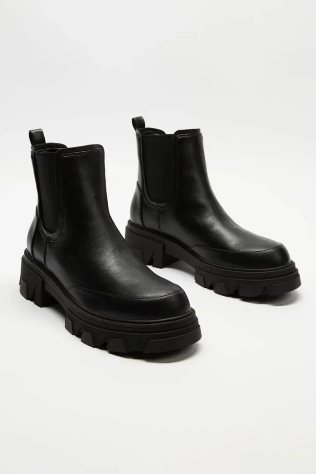 Black chunky leather Chelsea boots with thick soles on a white background.