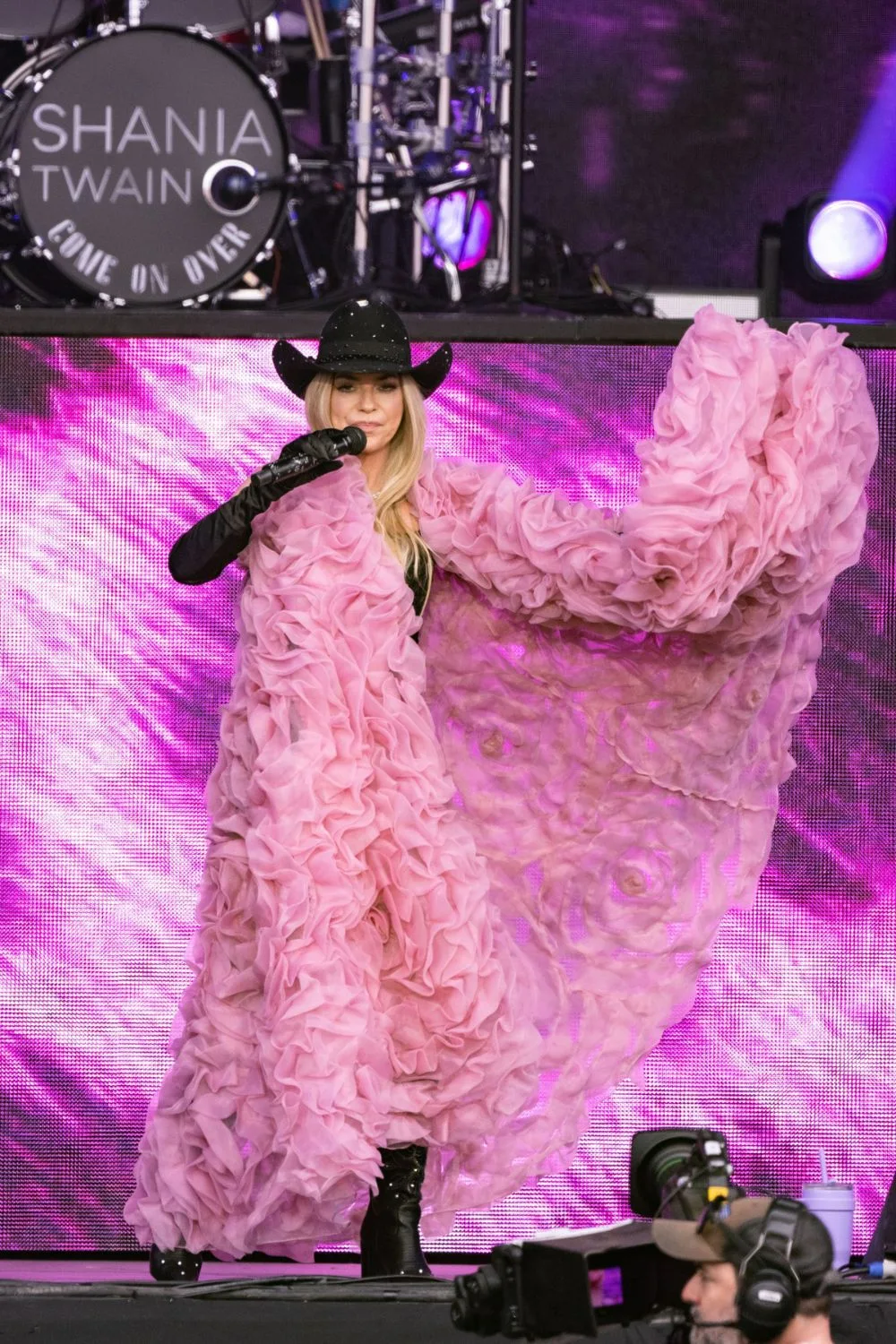 Shania Twain at Glastonbury in a  rhinestone cowboy hat and pink ruffled cape. 
