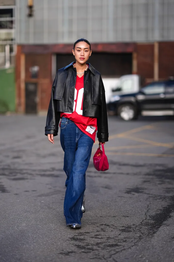 COPENHAGEN street style wearing black leather jacket, blue denim jeans and red bag,