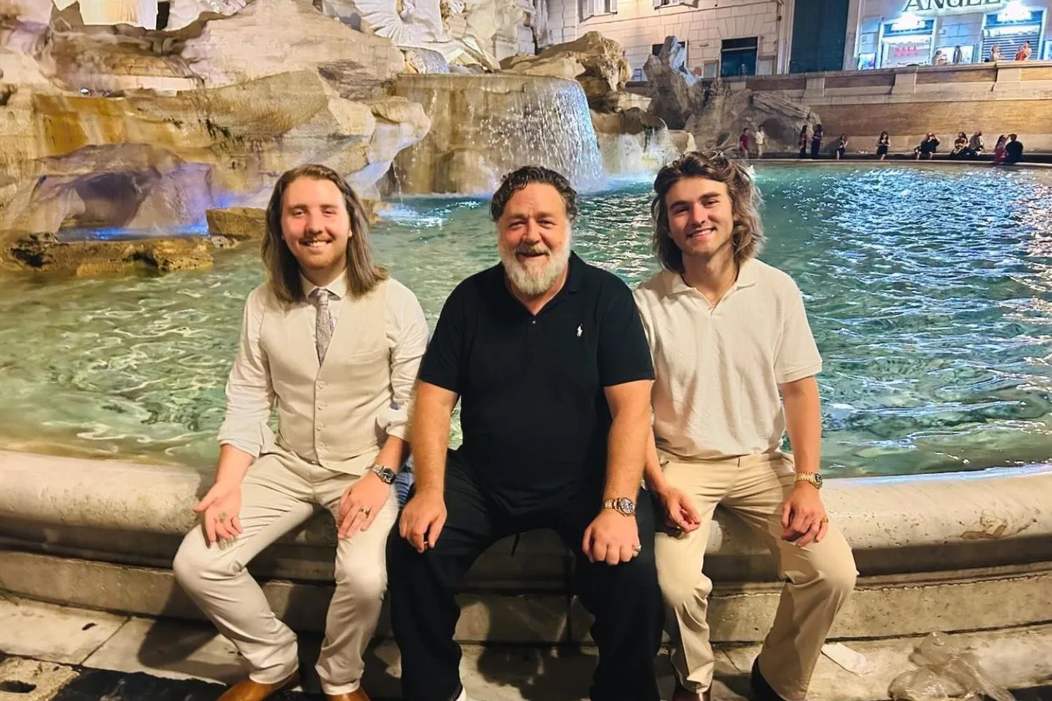 Russell Crowe and sons sitting at the Trevi Fountain in Italy