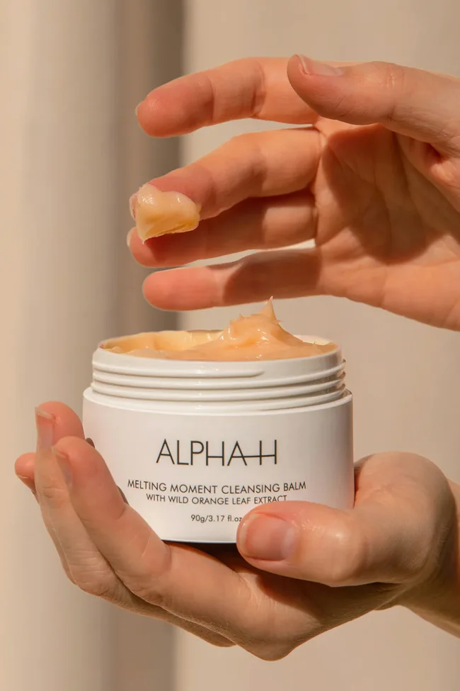 Hand holding the ALPHA-H cleansing balm.