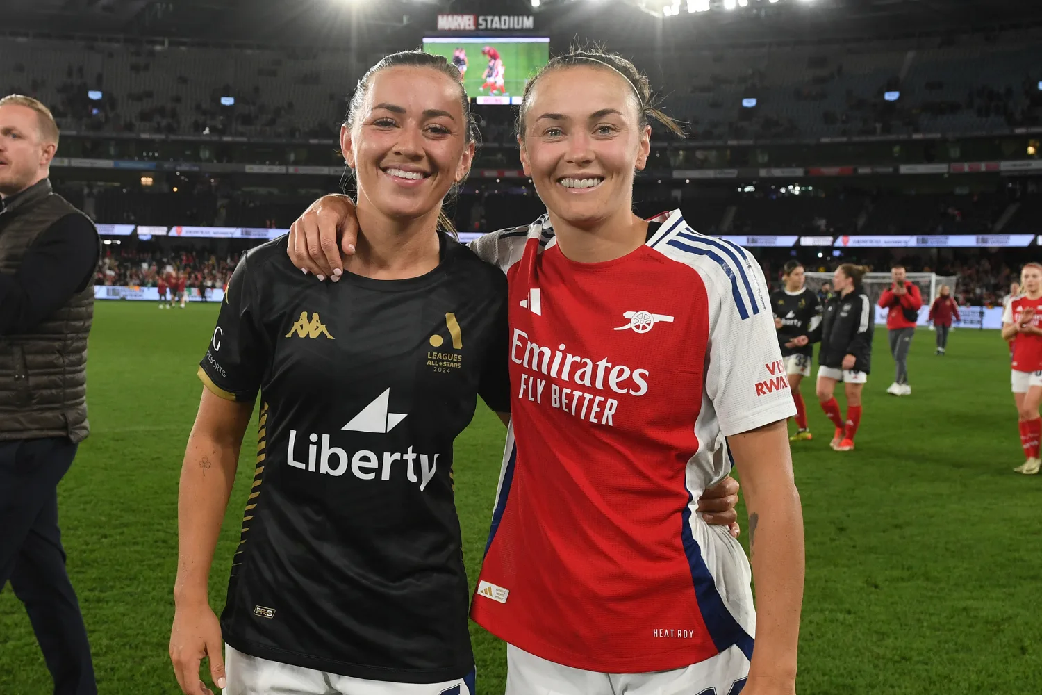 Katie McCabe and Caitlin Foord standing on a football pitch.