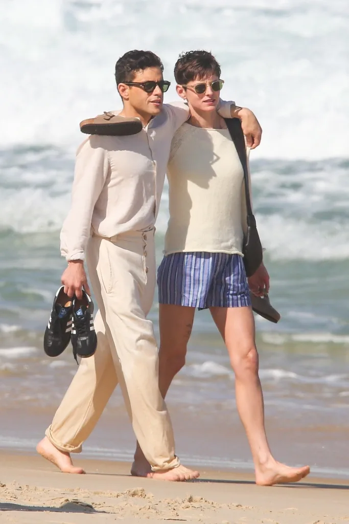 Emma Corrin and Rami Malek walking on the beach
