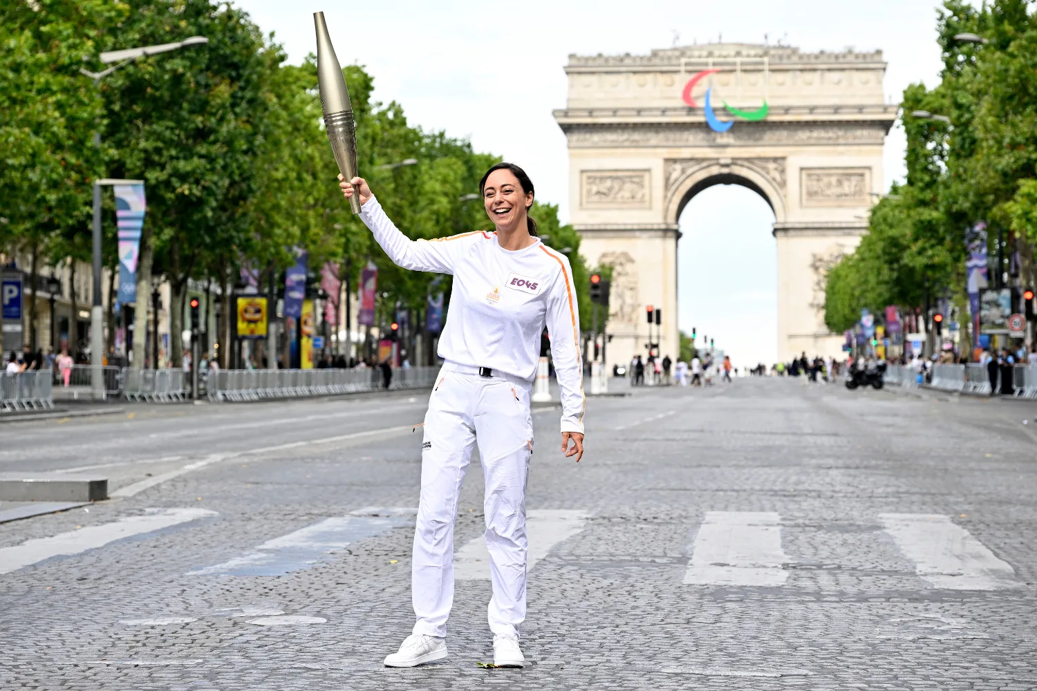 Woman carrying the Olympic Torch in front of the Arc de Triomphe.