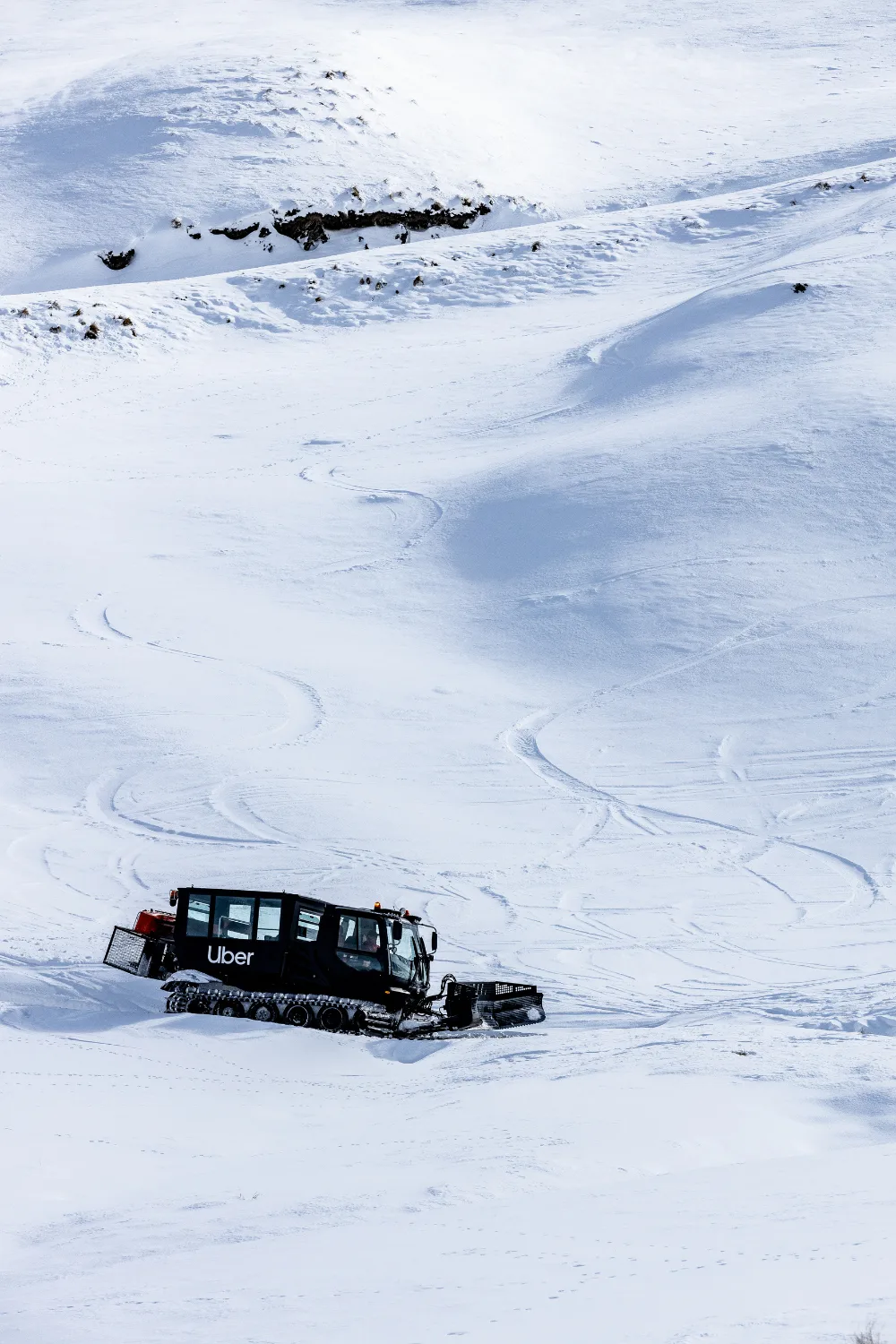 A black Uber snowcat on a snowy mountain. 