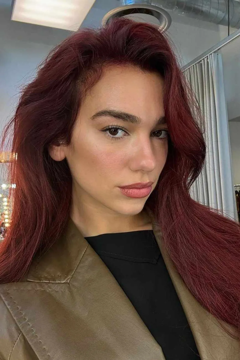 Dua Lipa with red hair wearing a green blazer.