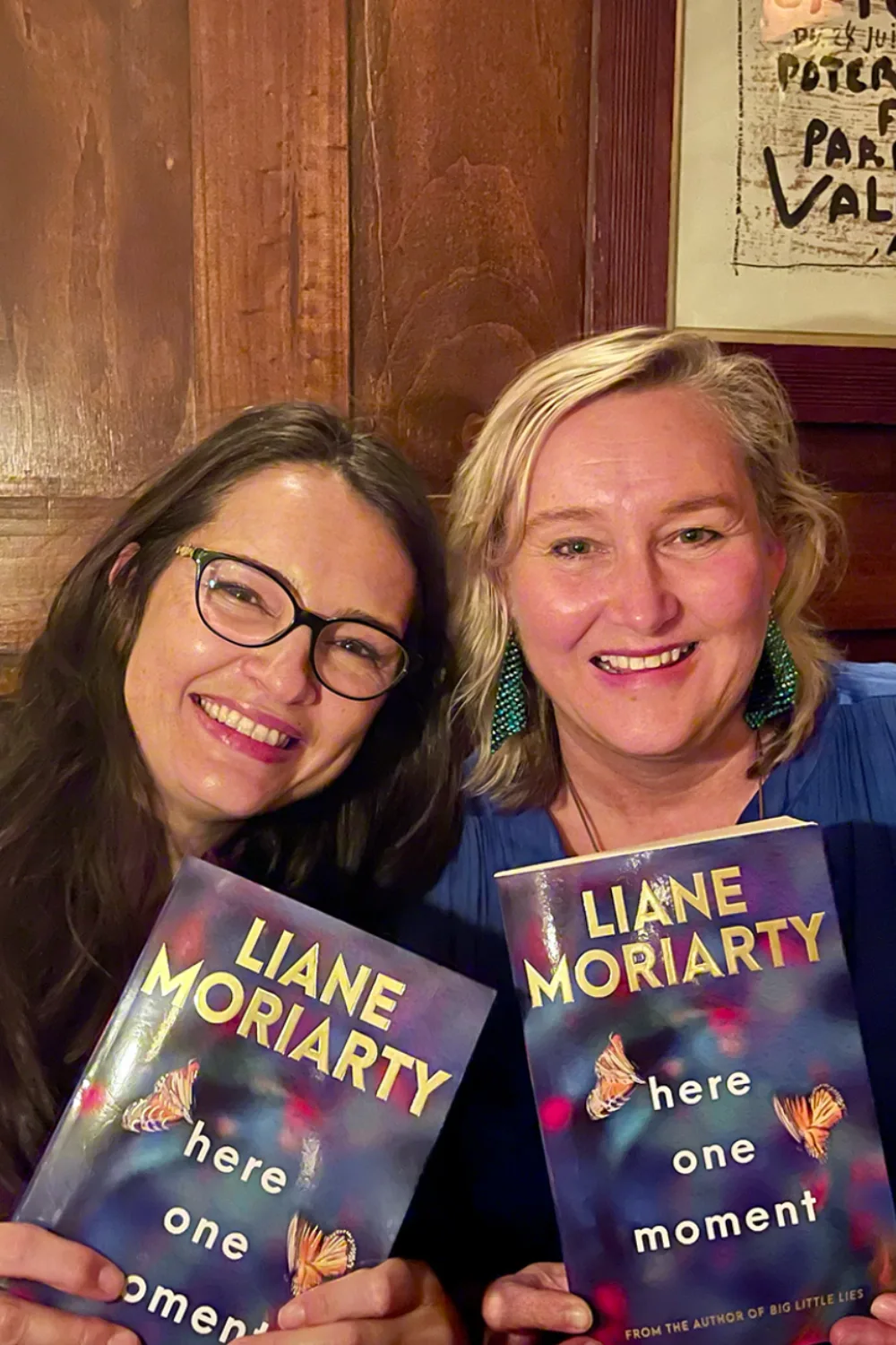 Two women holding Liane Moriarty's Here One Moment book.