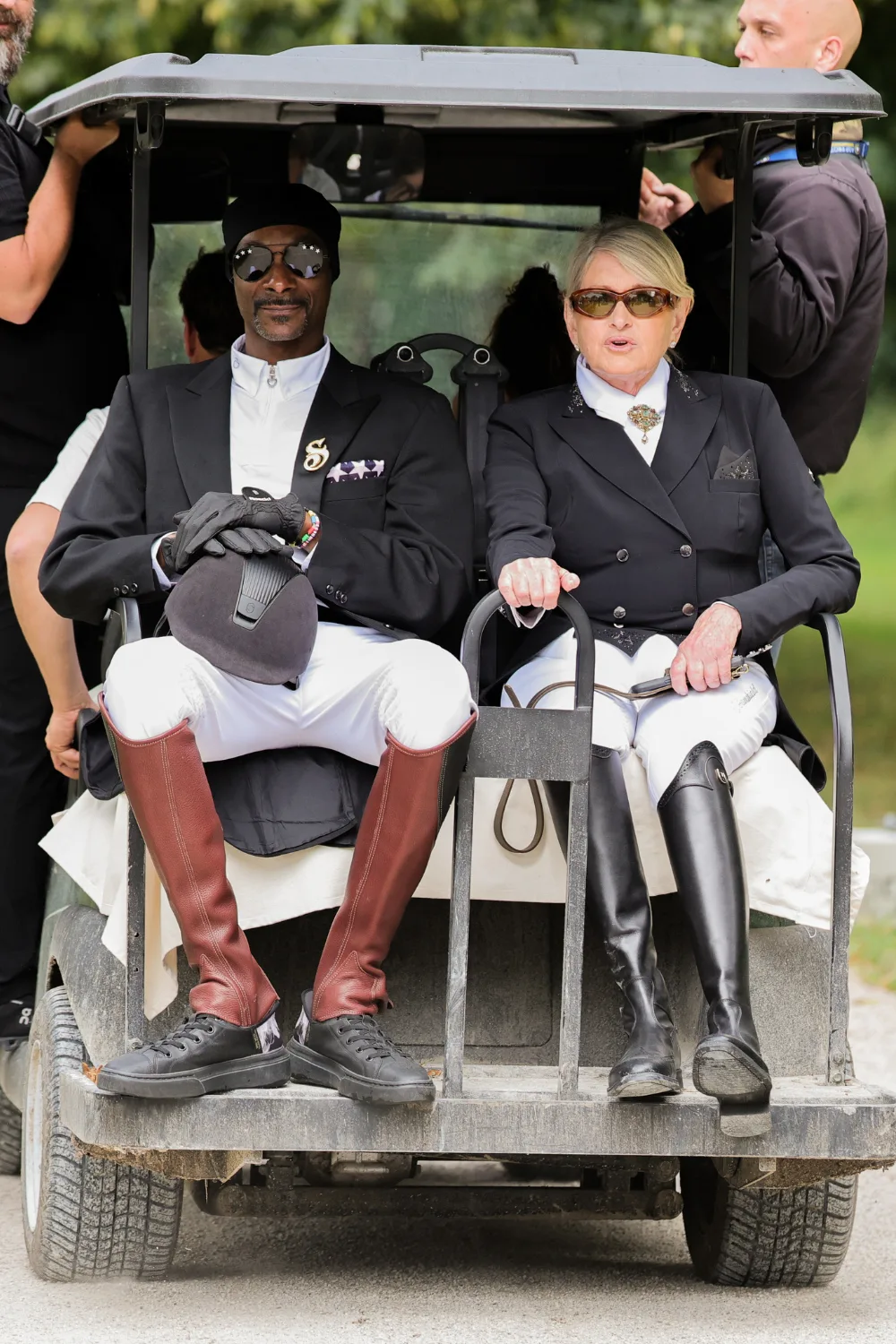 Martha Stewart and Snoop Dogg wearing equestrian outfits on the back of a golf cart.