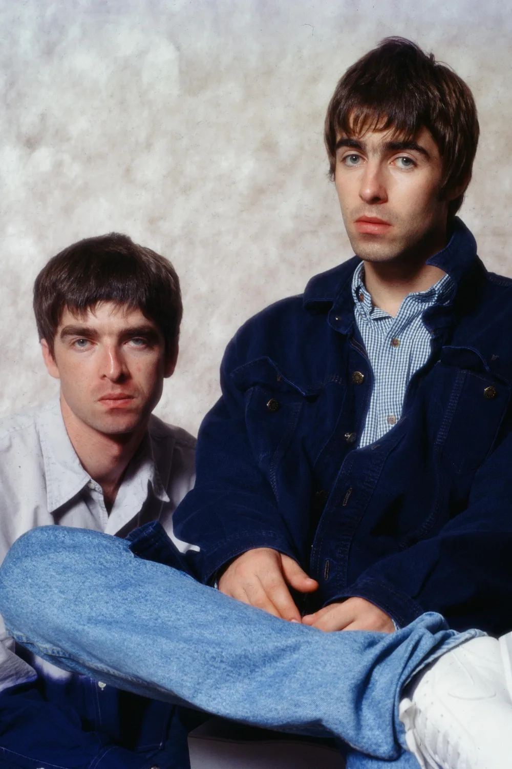 A seated portrait of Noel and Liam Gallagher. 