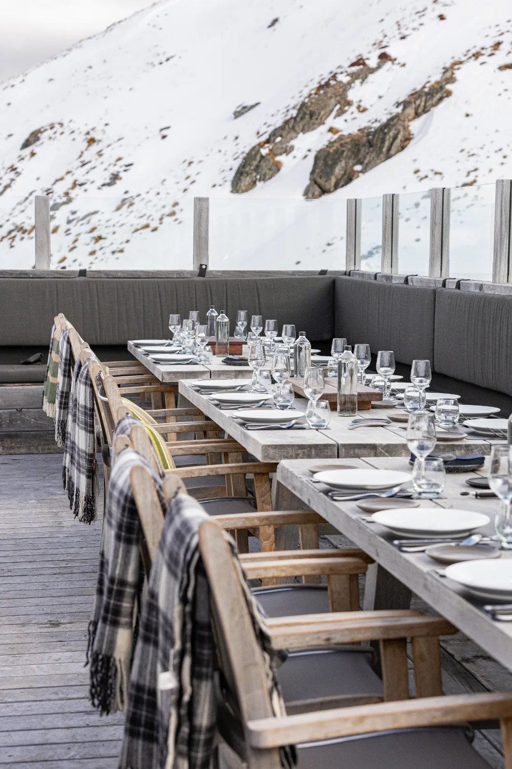 A long outdoor dining table surrounded by a snowy backdrop. 