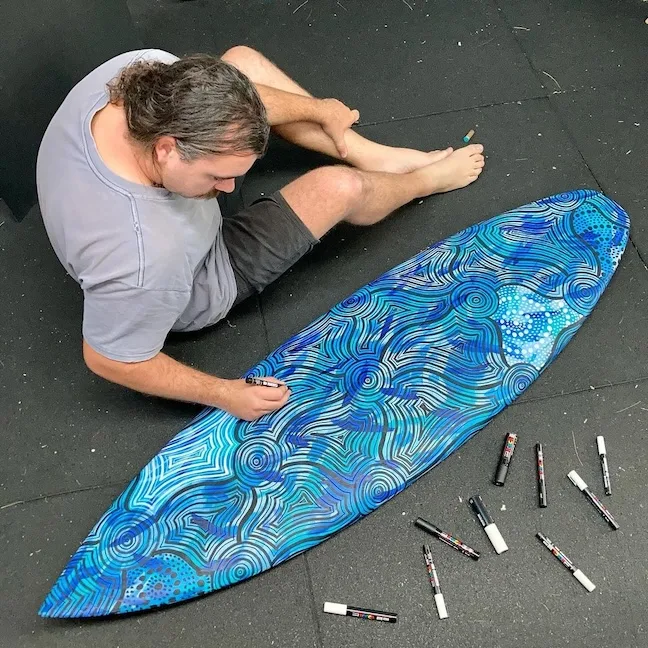 Artist painting a surfboard