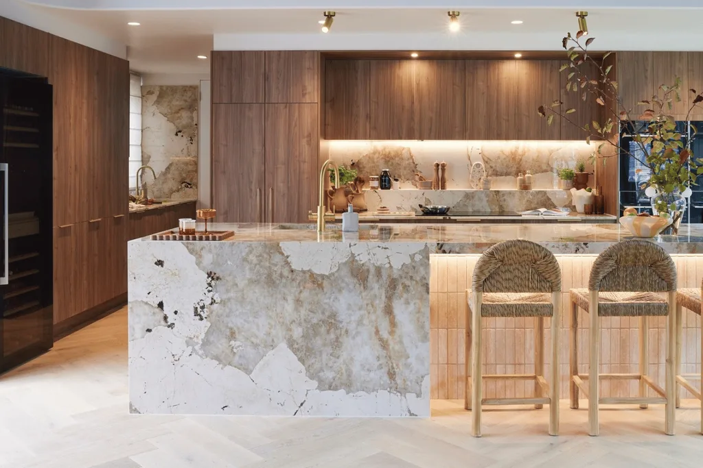 a light marble kitchen surrounded by dark wood.