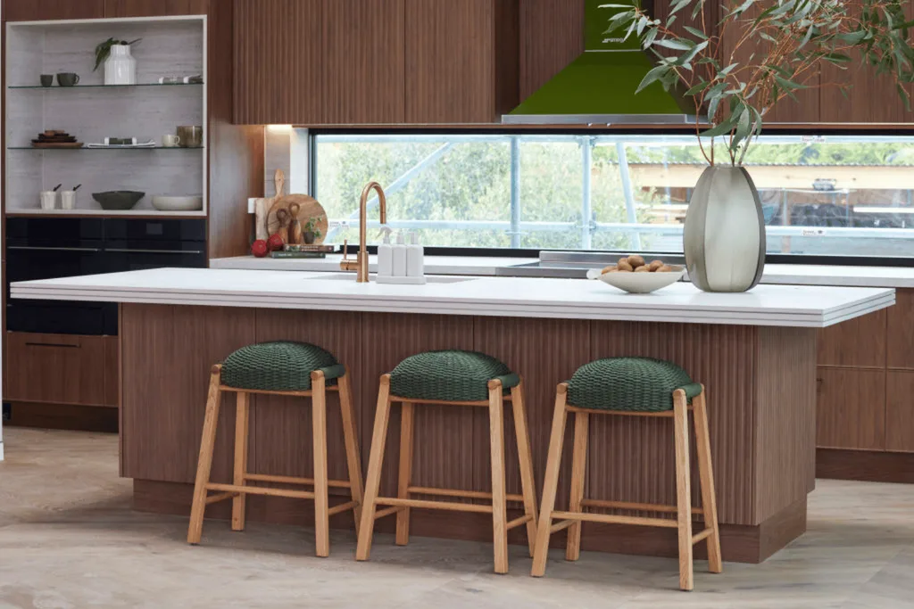 a dark wood kitchen with green bar stools and appliances.