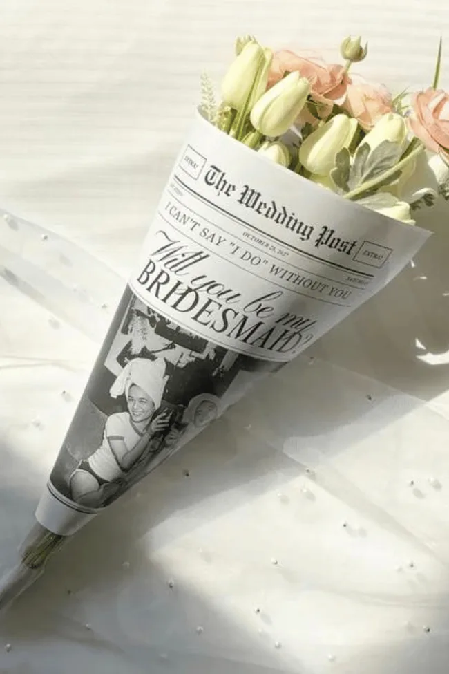 A roll of newspaper holding a bouquet of flowers.
