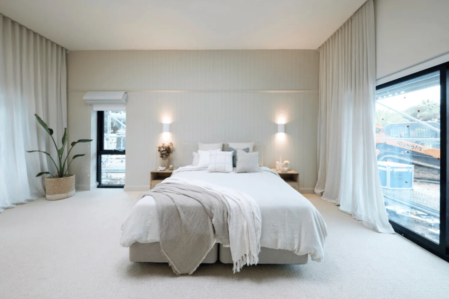 A bed sitting in the middle of a master bedroom surrounded by two lamps. 