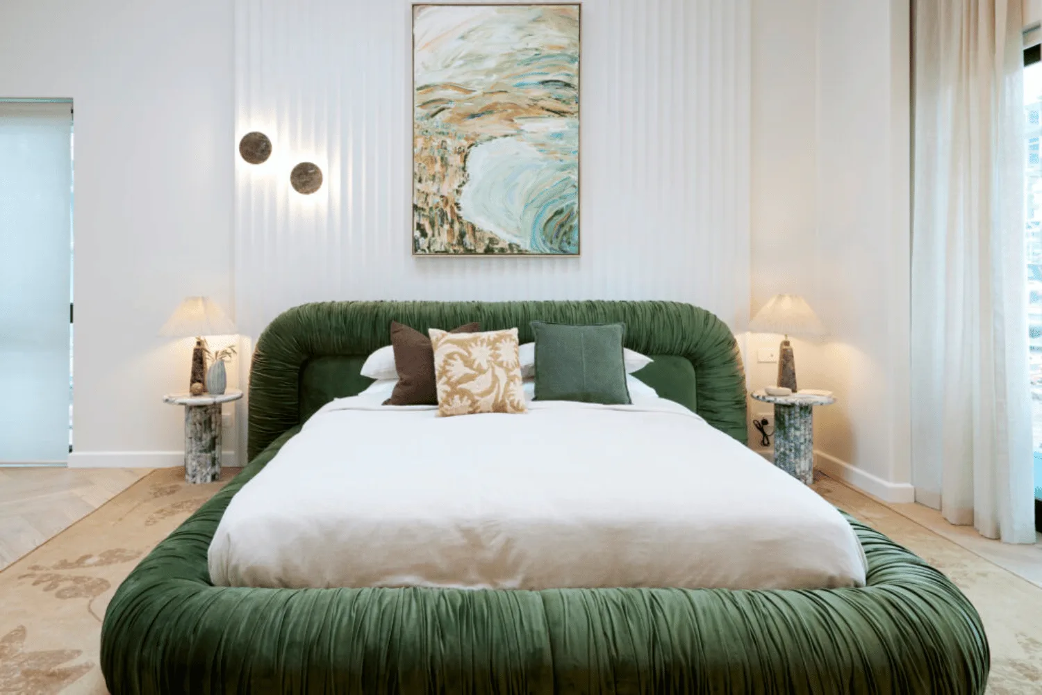 A green velvet bedframe in an all-white master bedroom. 