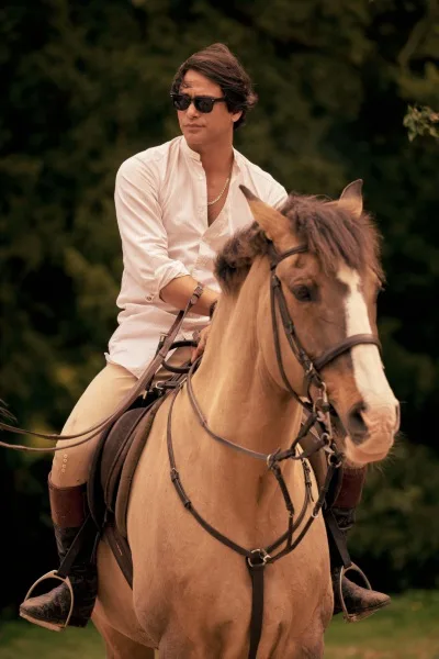 Luke Pasqualino sits on a horse in character as Basil in scene from Rivals.