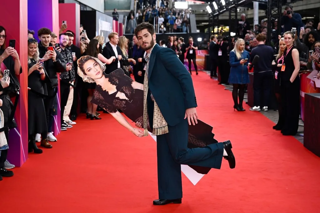 Andrew Garfield holding cardboard cut out of Florence Pugh.