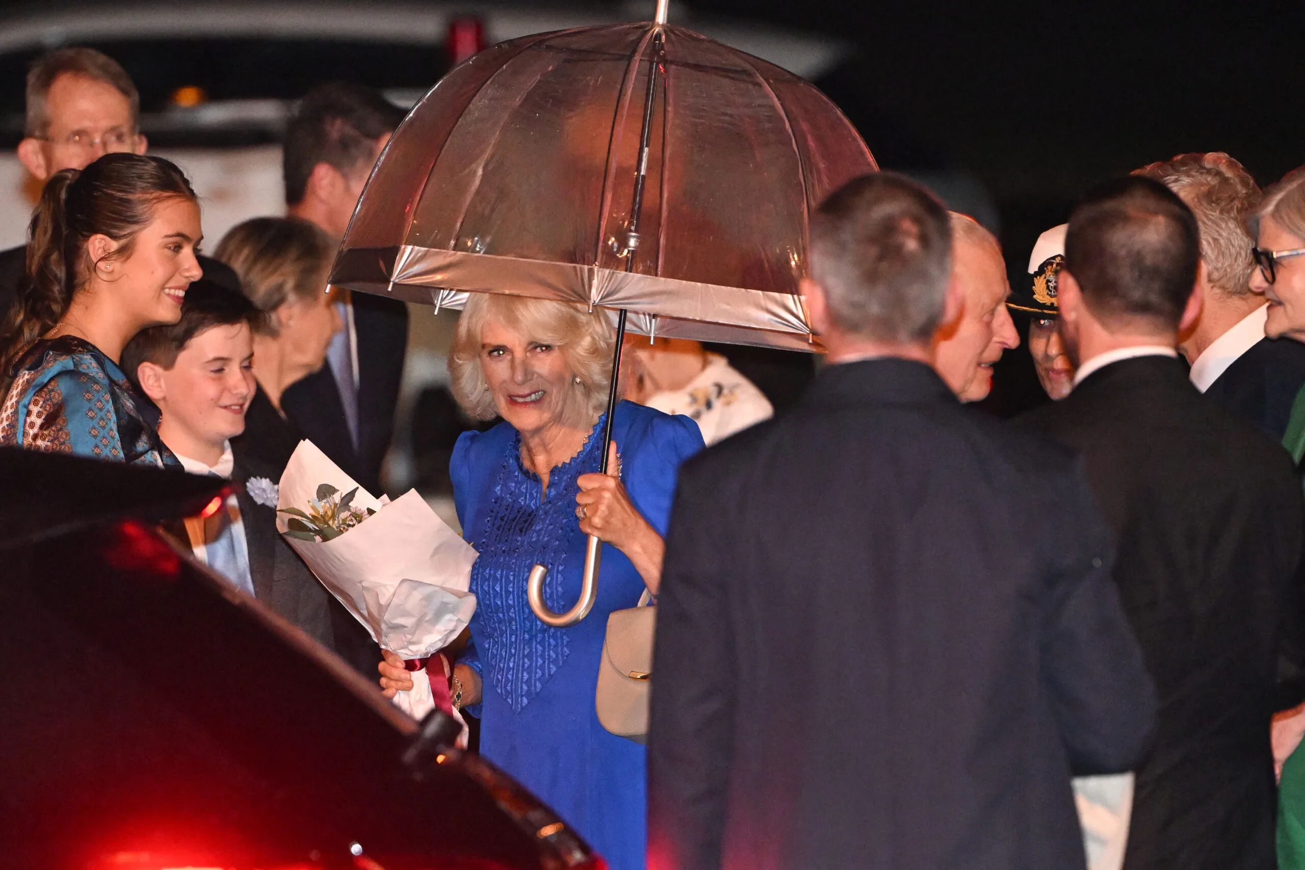 Camilla is presented flowers upon landing in australia