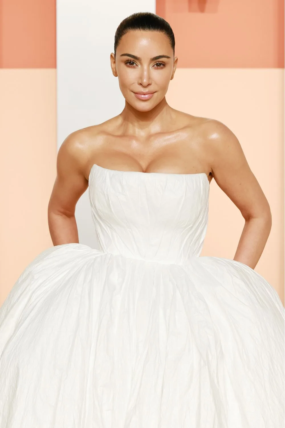 Kim Kardashian in a white dress with slicked back hair.