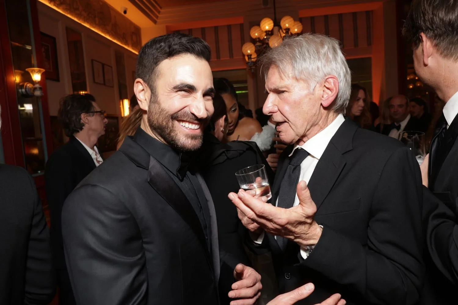 Brett Goldstein smiles while talking with Harrison Ford