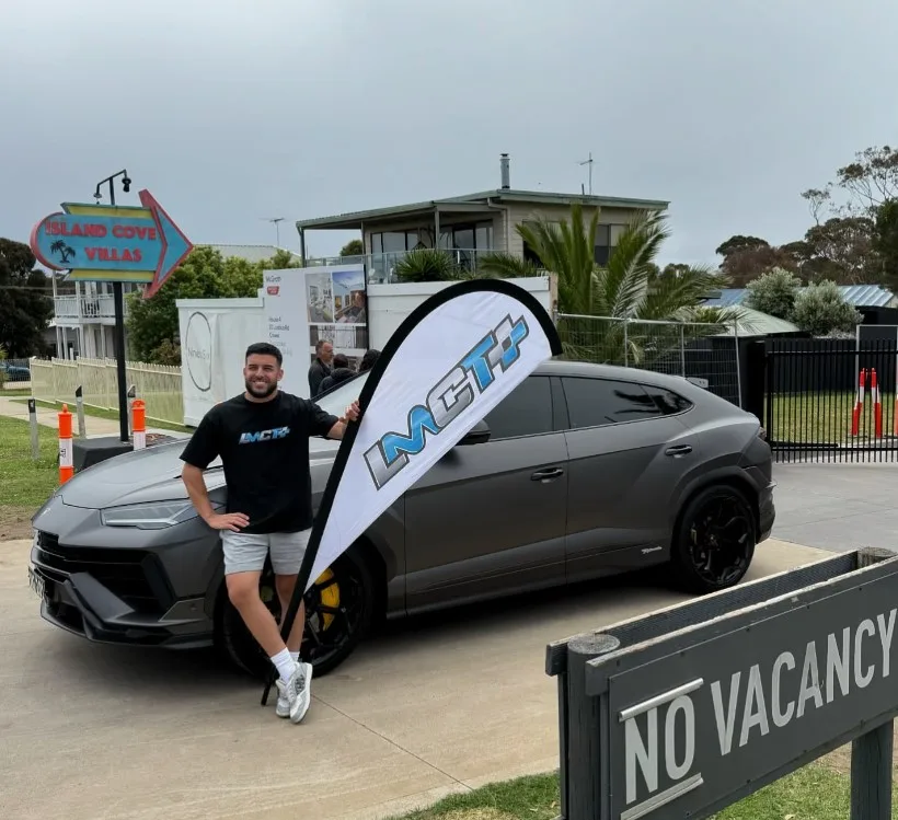 Adrian Portelli standing in front of a black car.