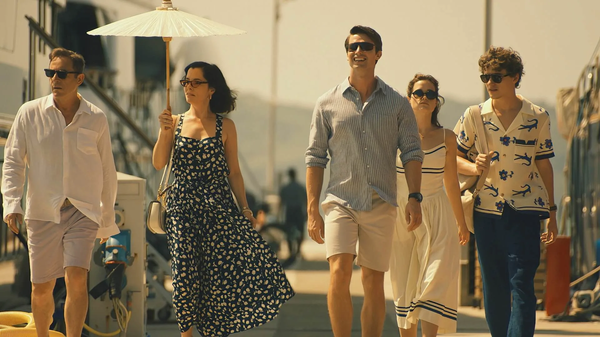 Jason Isaacs, Parker Posey, Patrick Schwarzenegger, Sarah Catherine Hook and Sam Nivola walk side by side in a still from Season 3 of the White Lotus 