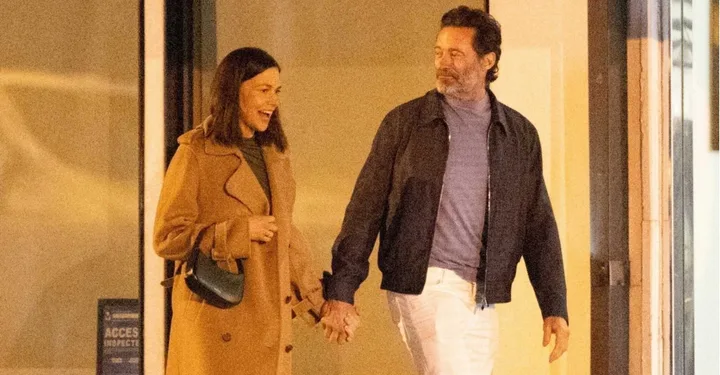 Sutton Foster and Hugh Jackman hold hands walking along the street