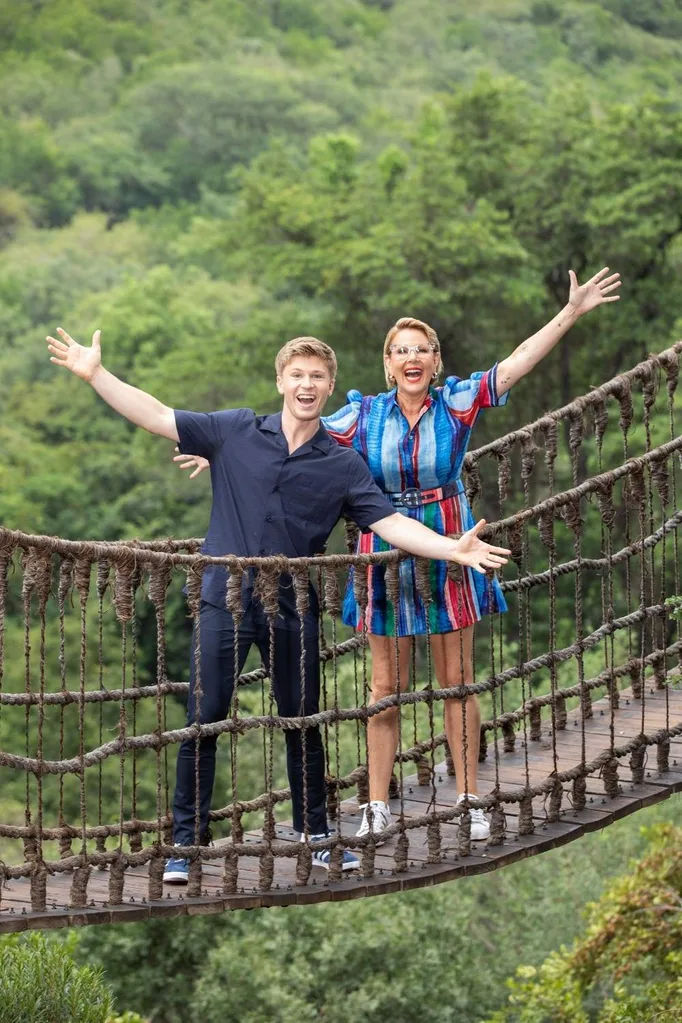 Robert Irwin and Julia Morris stand on a wooden bridge in Africa.