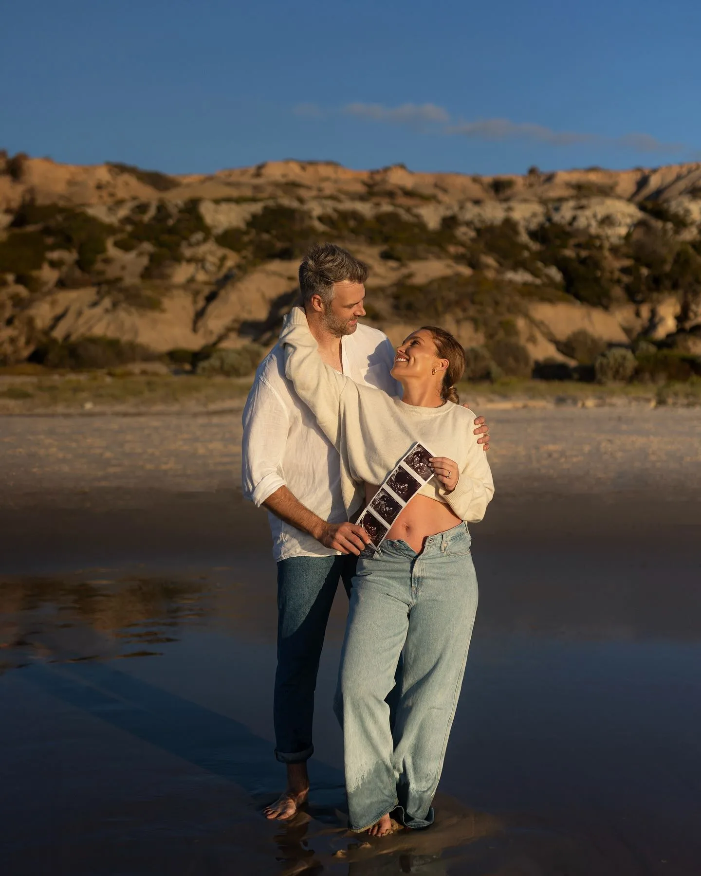 Keegan Brooksby and Abbey Holmes embrace on the beach 