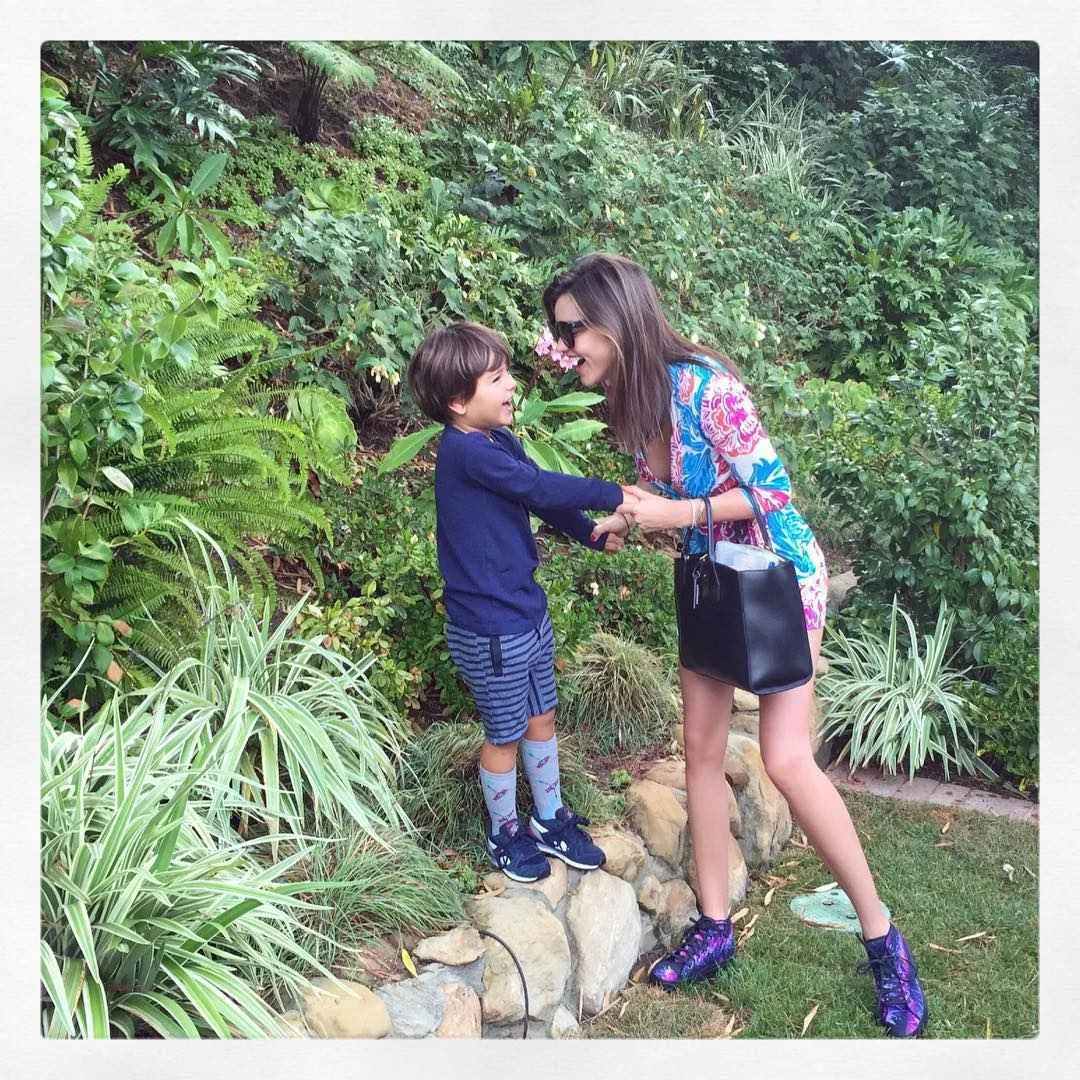 Miranda Kerr holds hands and laughs with her son Flynn in a garden