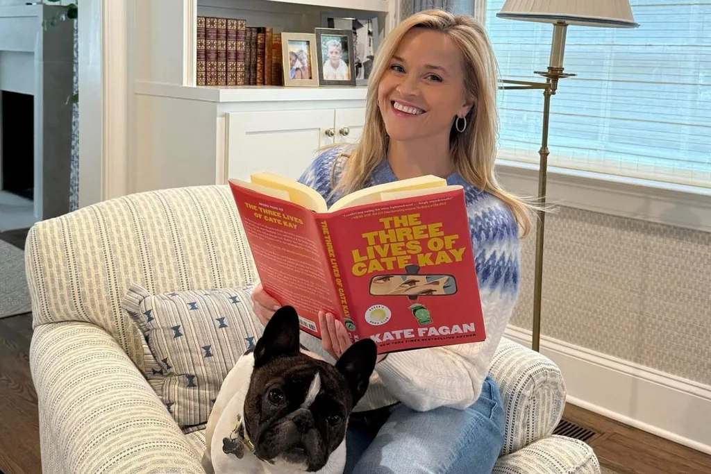 Reese Witherspoon holds book The Three Lives of Cate Kay