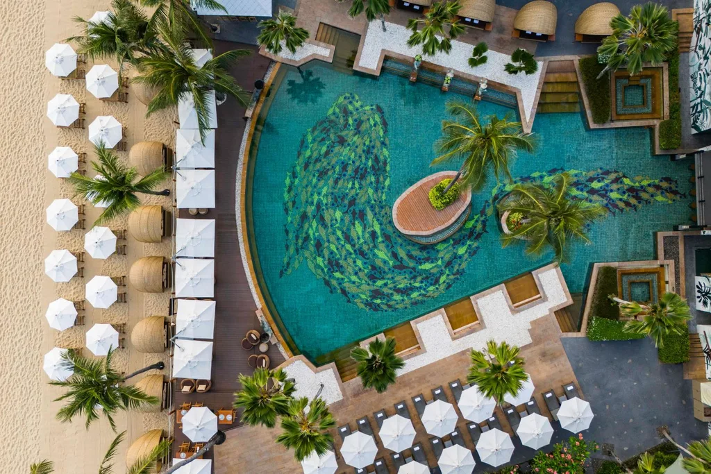 Aerial view of a hotel pool surrounded by palm trees