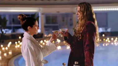 Anna Kendrick and Blake Lively clink champagne glasses in a scene from Another Simple Favor