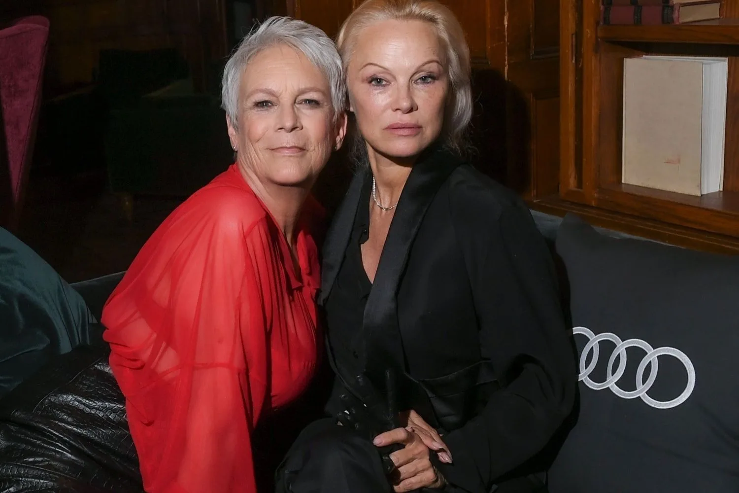 Jamie Lee Curtis in red sits next to Pamela Anderson in black